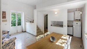 Eine moderne Küche mit weißen Schränken, einem Holztisch und einer Treppe, die in einen zweiten Stock führt.