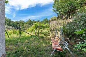 Un jardin avec une balançoire en métal, une clôture en bois et une pergola.