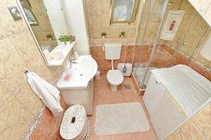 A bathroom with a sink, toilet, shower, and a small rug. - One Bedroom Apartment Sleeps 2 - Private Garden (Zadar)