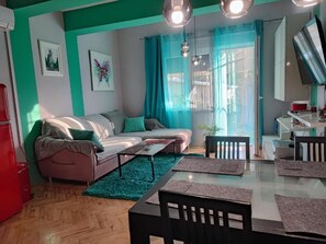A modern living room with a sofa, coffee table, dining table, chairs, and a kitchen area. - One Bedroom Apartment Sleeps 2 - Private Garden (Zadar)
