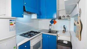 Eine Küche mit blauen Schränken, einem Gasherd, einer Spüle und einem weißen Kühlschrank.