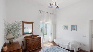 Ein Schlafzimmer mit Bett, Schminktisch, Spiegel und einem Fenster mit Vorhängen.
