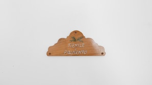 Een houten bord met de tekst 'TENILE e PALMENTO' en een decoratief element.