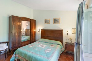 A bedroom with a bed, wooden wardrobe, and a mirror. - Le Tore – Palmento Room with Private Terrace, Shared Garden and Wi-Fi (Massa Lubrense)