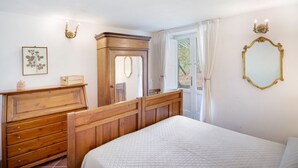 A bedroom with a wooden bed, a dresser, a mirror, and a door leading to a balcony. - Le Tore – Volta 2 Room with Terrace, Shared Garden, and Wi-Fi (Massa Lubrense)