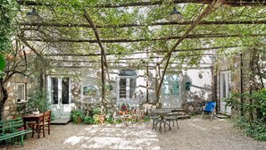 An outdoor patio with a table and chairs, a blue chair, and a stone wall. - Le Tore – Volta 2 Room with Terrace, Shared Garden, and Wi-Fi (Massa Lubrense)