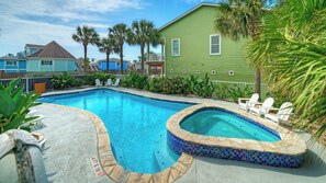 Ein Pool mit Whirlpool, umgeben von einer Betonplattform und Palmen.