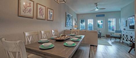 A dining area with a long wooden table, chairs, and a ceiling fan.