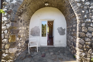 Un'apertura ad arco in pietra conduce a una stanza con una panca e un tavolo.