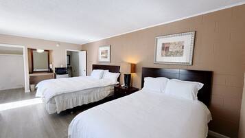 Habitación de hotel con dos camas, un escritorio, una silla, un espejo y un cuadro en la pared.