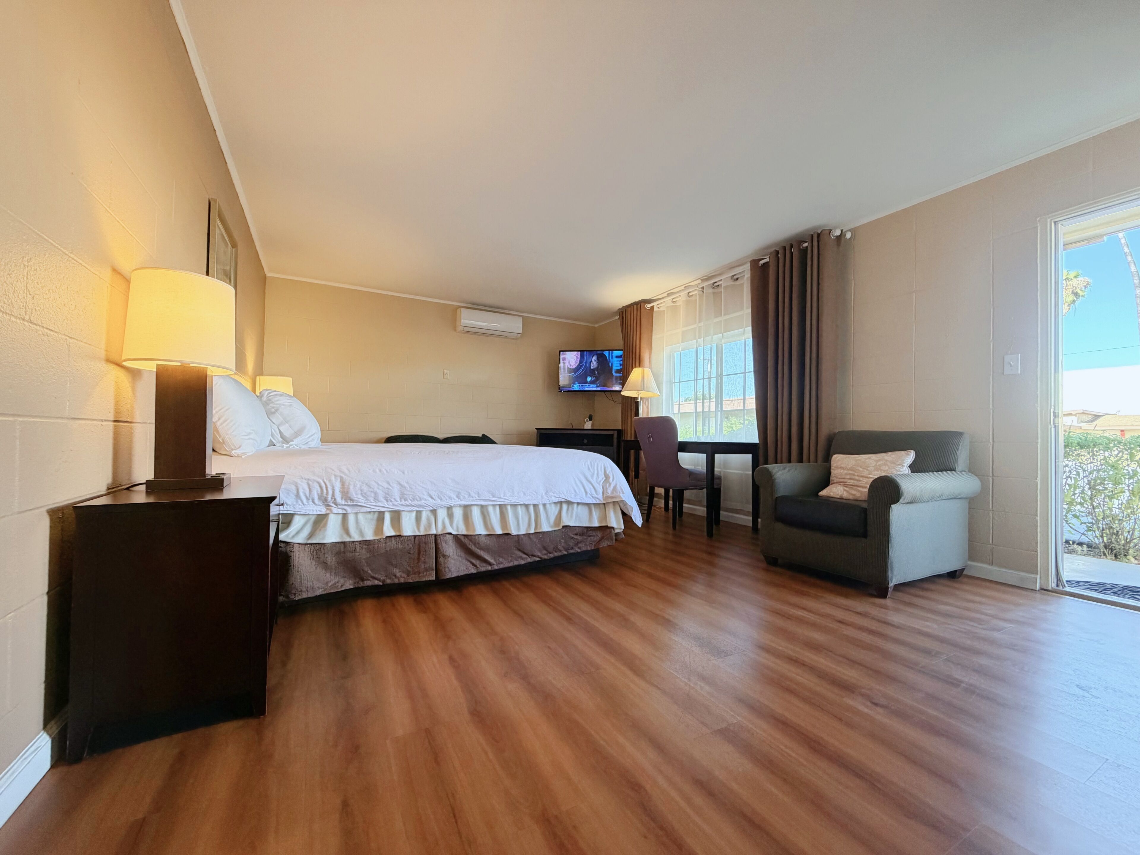 Une chambre d’hôtel avec un lit, un bureau et une chaise, une télévision et une vue par la fenêtre.