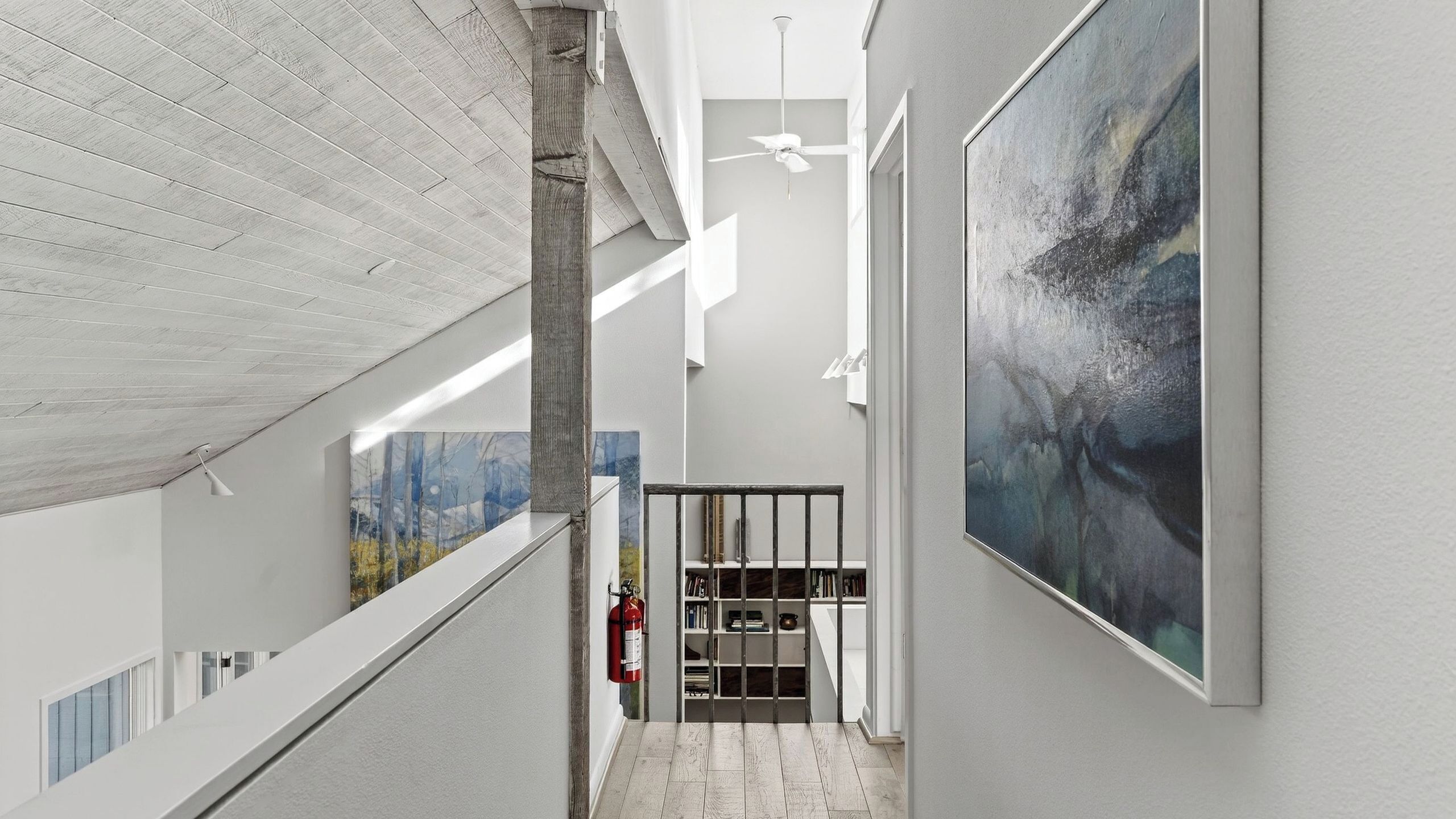 A modern interior with a staircase, large abstract paintings, and a minimalist design.