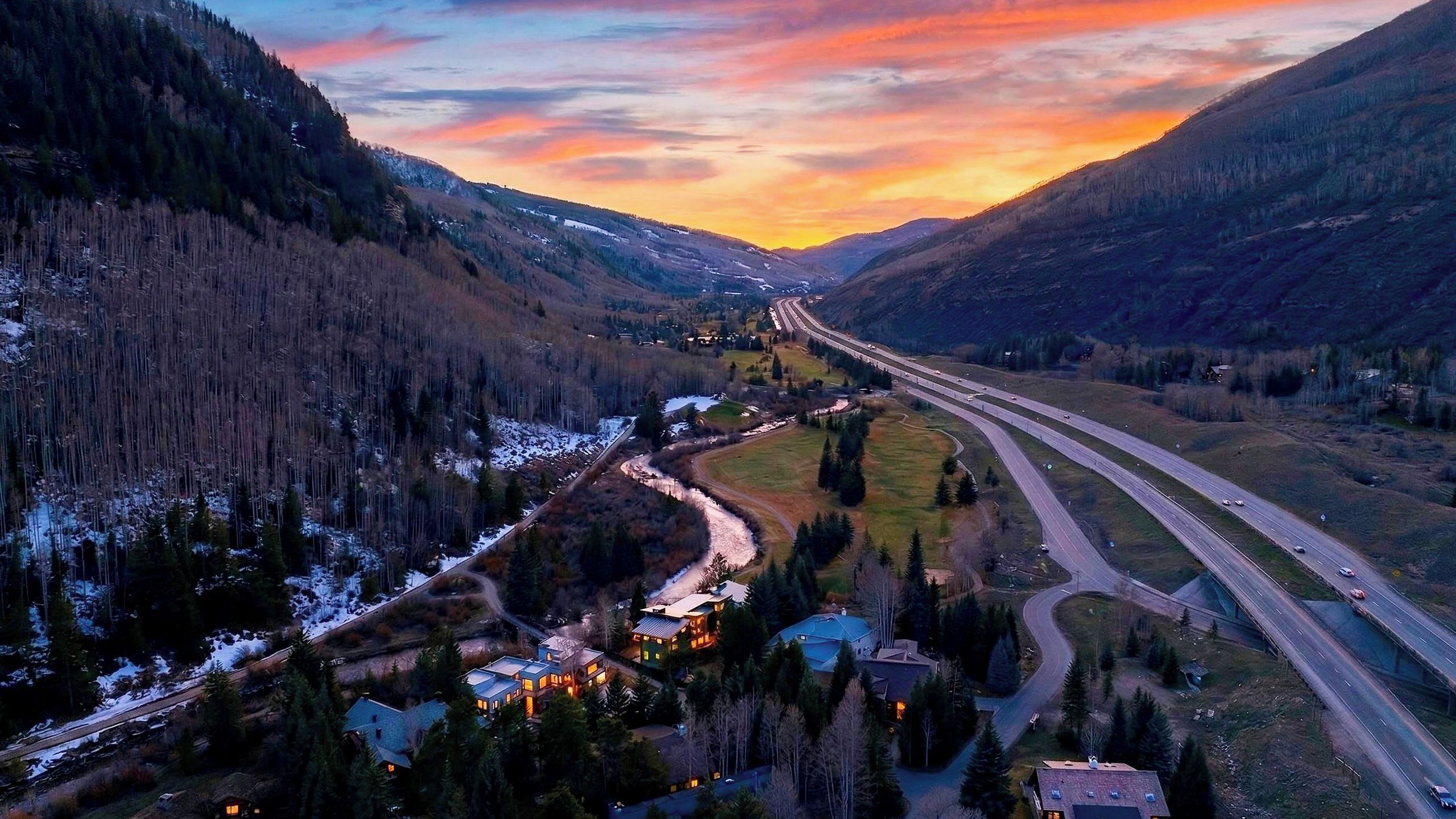 Un valle con una autopista, casas y un río.