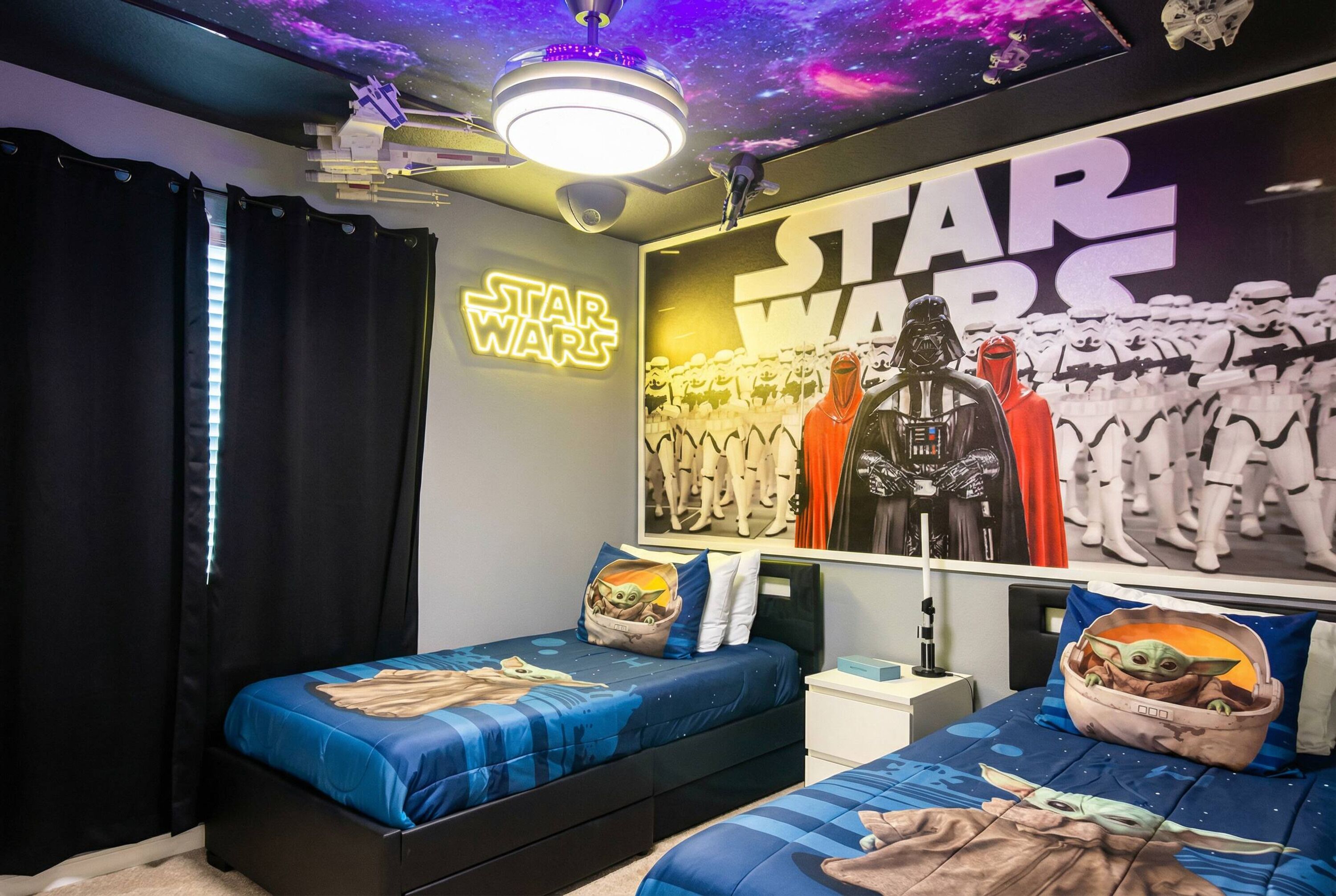 Une chambre à coucher sur le thème de Star Wars, avec deux lits, des affiches de Star Wars et un plafond décoré sur le thème de la galaxie.