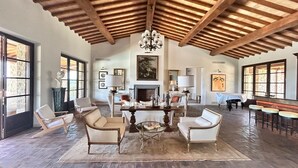 A spacious living room with a high ceiling, a fireplace, and a dining area with a round table and chairs.