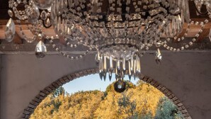 A balcony with a view of a hilly landscape, a wrought iron fence, and a decorative chandelier.
