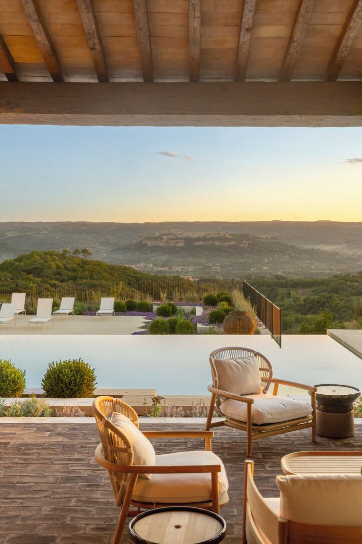 An outdoor seating area with lounge chairs and a table, overlooking a scenic landscape.