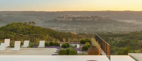 Espaço ao ar livre com cadeiras de descanso e uma mesa, com vista para uma paisagem deslumbrante.