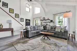 Un salon spacieux avec un grand canapé d’angle, une table basse et un escalier.