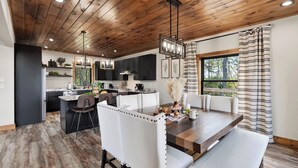A modern kitchen with dark cabinets, a central island, and pendant lighting. - Priddy Secluded by Avantstay Hot Tub + Expansive Deck + Game Room + Home Theater (Sevierville)
