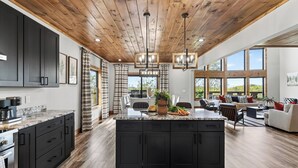 A spacious kitchen with a central island, dark cabinetry, and a wooden ceiling. - Priddy Secluded by Avantstay Hot Tub + Expansive Deck + Game Room + Home Theater (Sevierville)