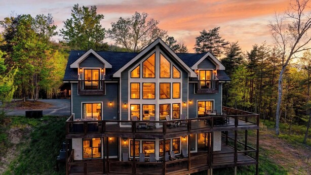 A two-story house with a balcony, large windows, and a deck. - Priddy Secluded by Avantstay Hot Tub + Expansive Deck + Game Room + Home Theater (Sevierville)