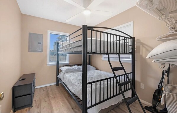 A bunk bed room with a ceiling fan, a small desk, and a vacuum cleaner. - 2 bedroom condo in Wildwood with parking. 2 blocks from the beach & amusements. (Wildwood)