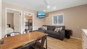 A compact living space with a dining table, sofa, and a ceiling fan.