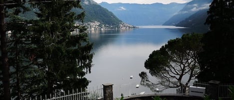 A lake surrounded by mountains, a white fence, and some trees.