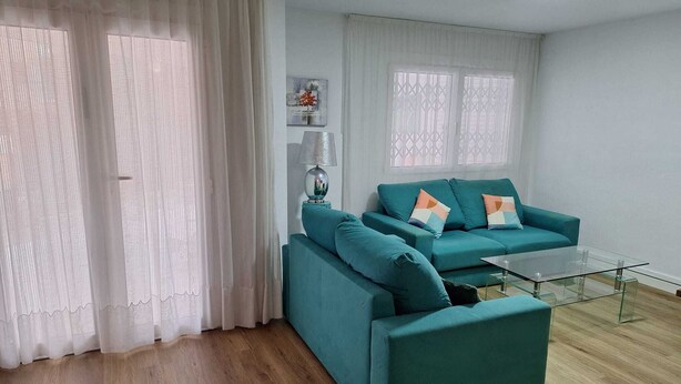 A living room with teal sofas, a glass coffee table, and a painting on the wall. - Townhouse with pool in Benicasim 400 m from El Torreon beach (Benicàssim)