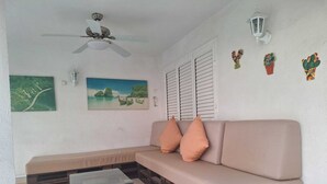 A room with a sofa, a ceiling fan, a table, and wall-mounted decorations. - Townhouse with pool in Benicasim 400 m from El Torreon beach (Benicàssim)