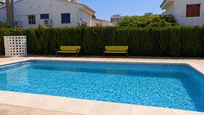 A swimming pool with two benches, surrounded by a hedge and buildings. - Townhouse with pool in Benicasim 400 m from El Torreon beach (Benicàssim)