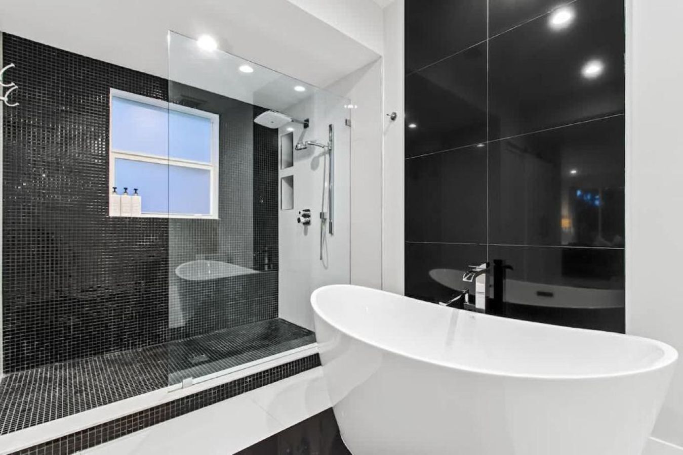 Une salle de bain moderne avec une baignoire sur pieds, une douche à parois de verre et un grand miroir.