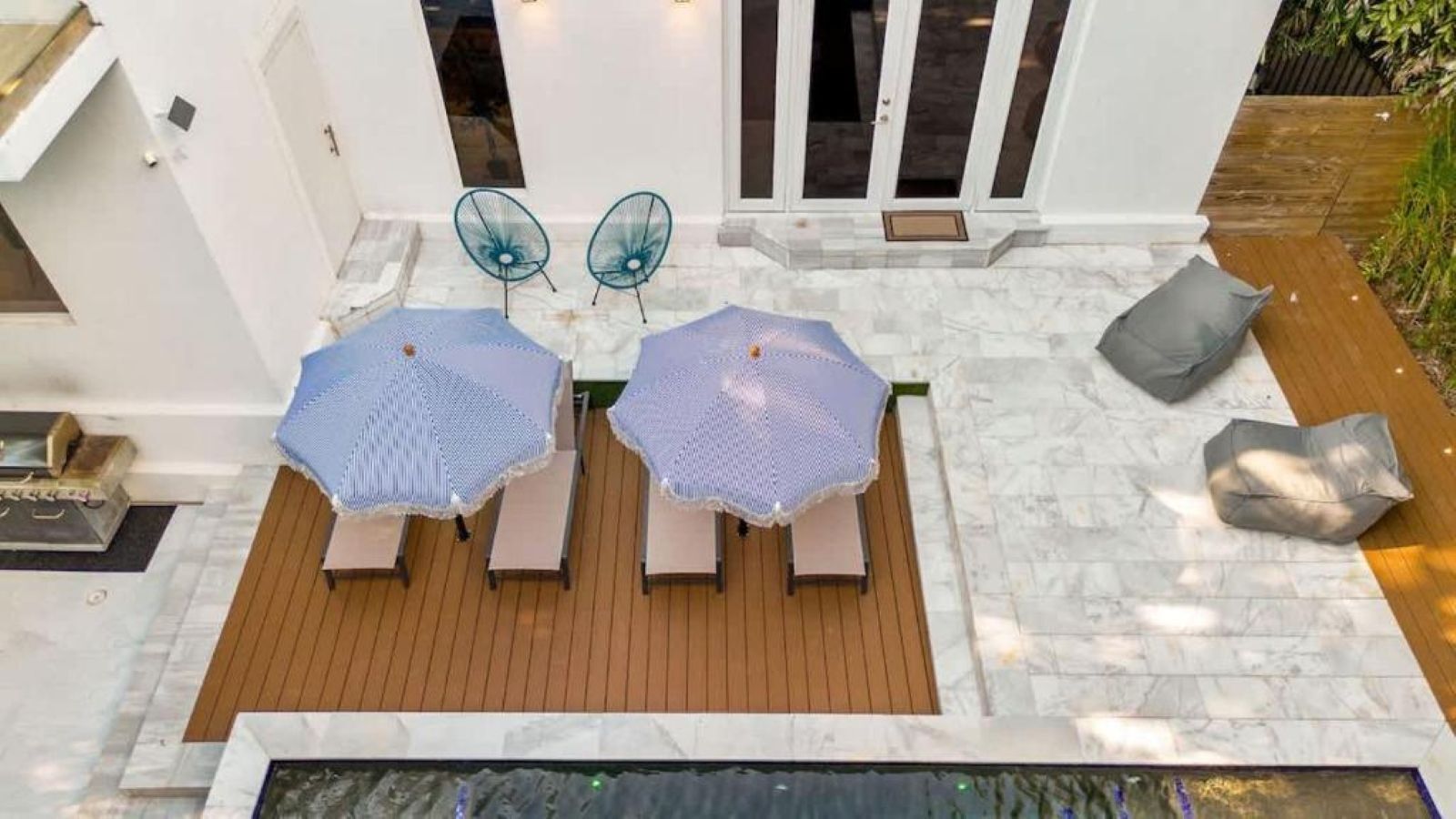 A patio with two lounge chairs and a table, a small pool, and a wooden deck.