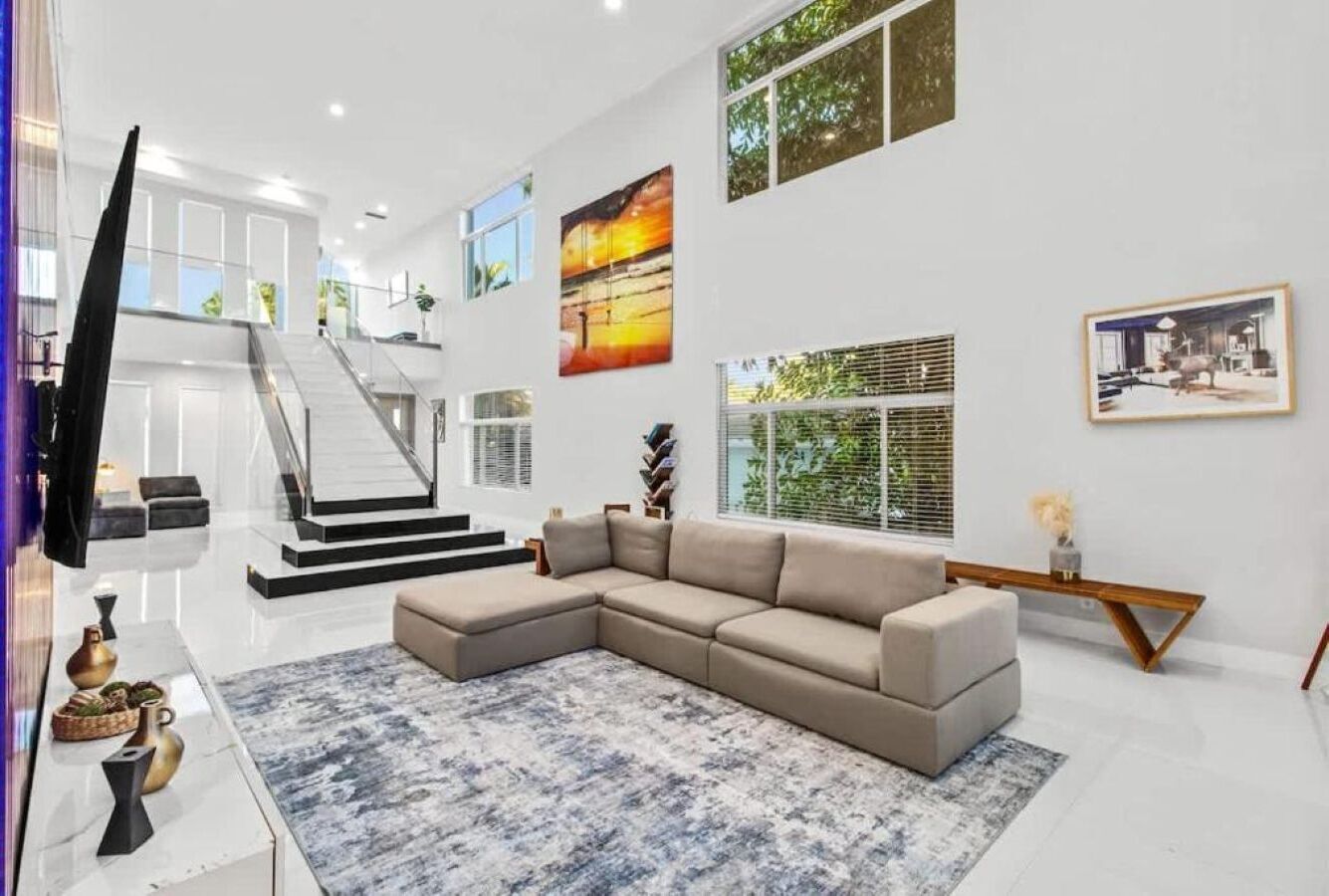 Een moderne woonkamer met een hoekbank, een flatscreen televisie en kunstwerken aan de muur.