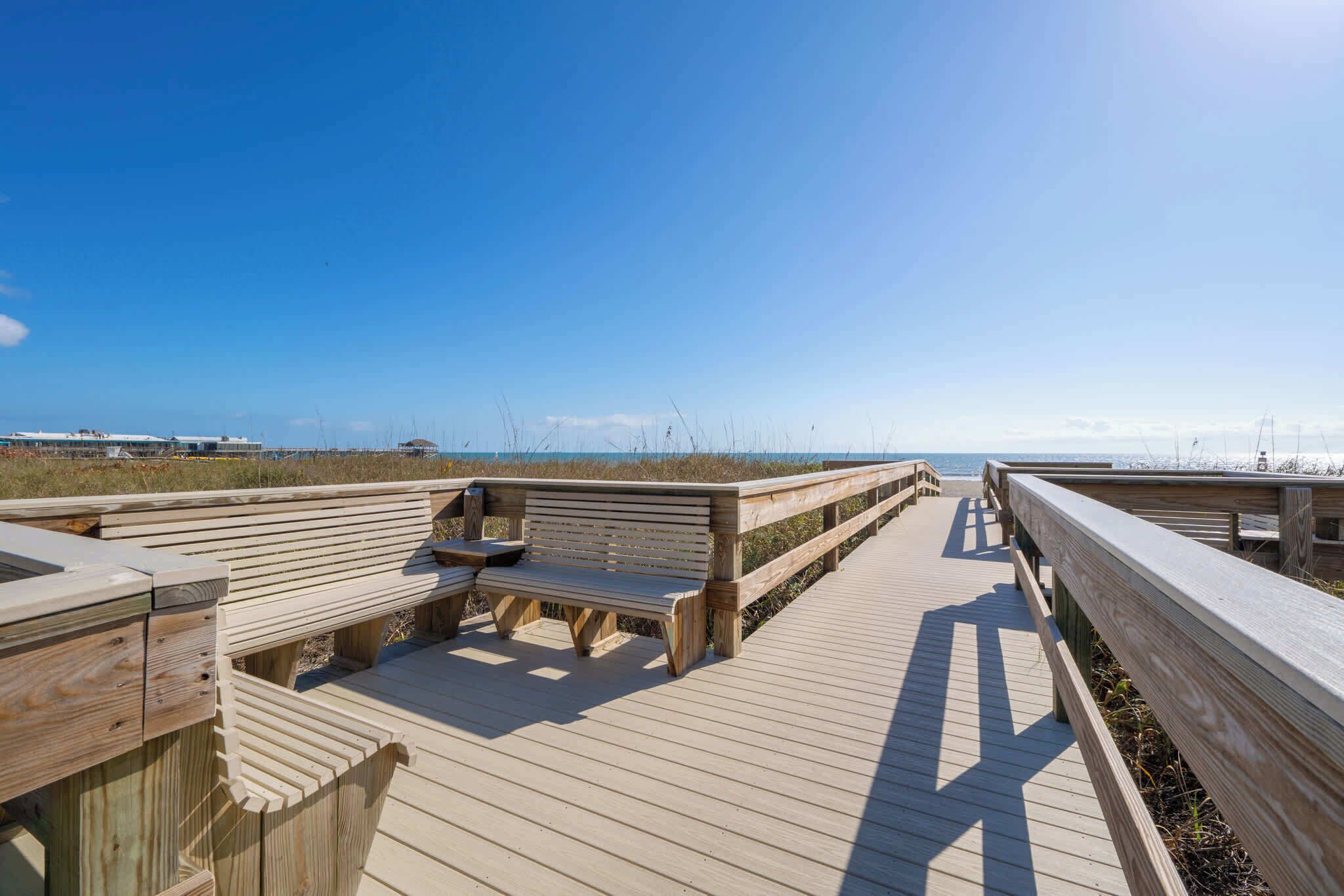 Een houten looppad met banken en uitzicht op het strand.