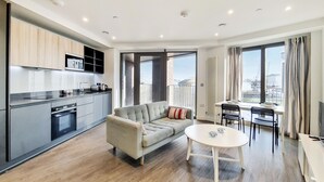 En modern lägenhet med kök, soffa, matbord och stora fönster med utsikt över staden.