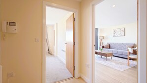 A hallway leading to a living area with a sofa, a coffee table, and a lamp. - Capital Stay - Two Bed Apartments Near Lcy (London)
