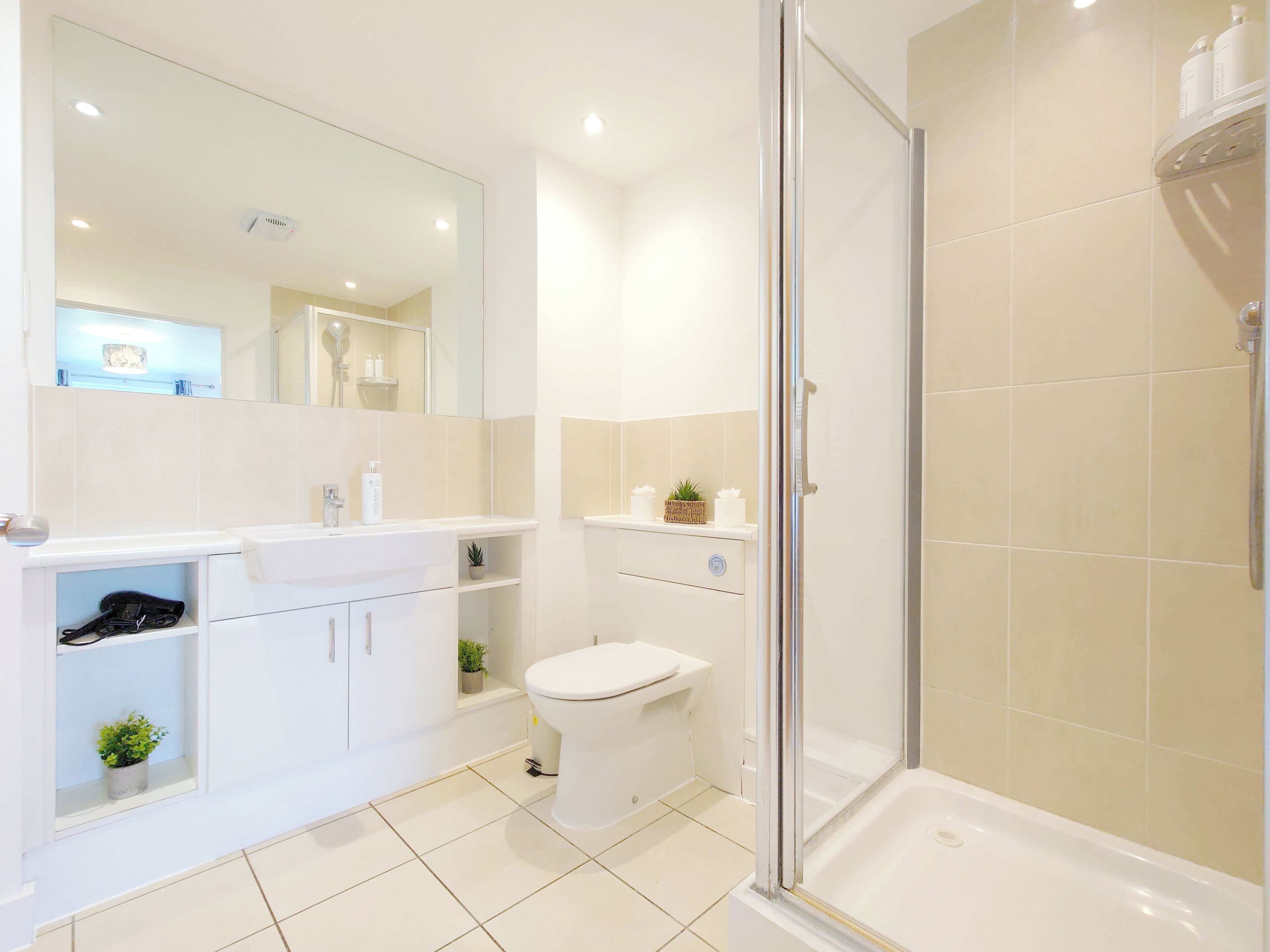 A modern bathroom with a glass shower enclosure, a white sink, and a toilet.