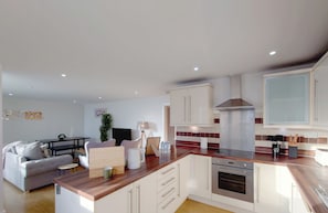 Eine moderne Küche mit weißen Schränken, einer Holz Arbeitsplatte und einem eingebauten Backofen.