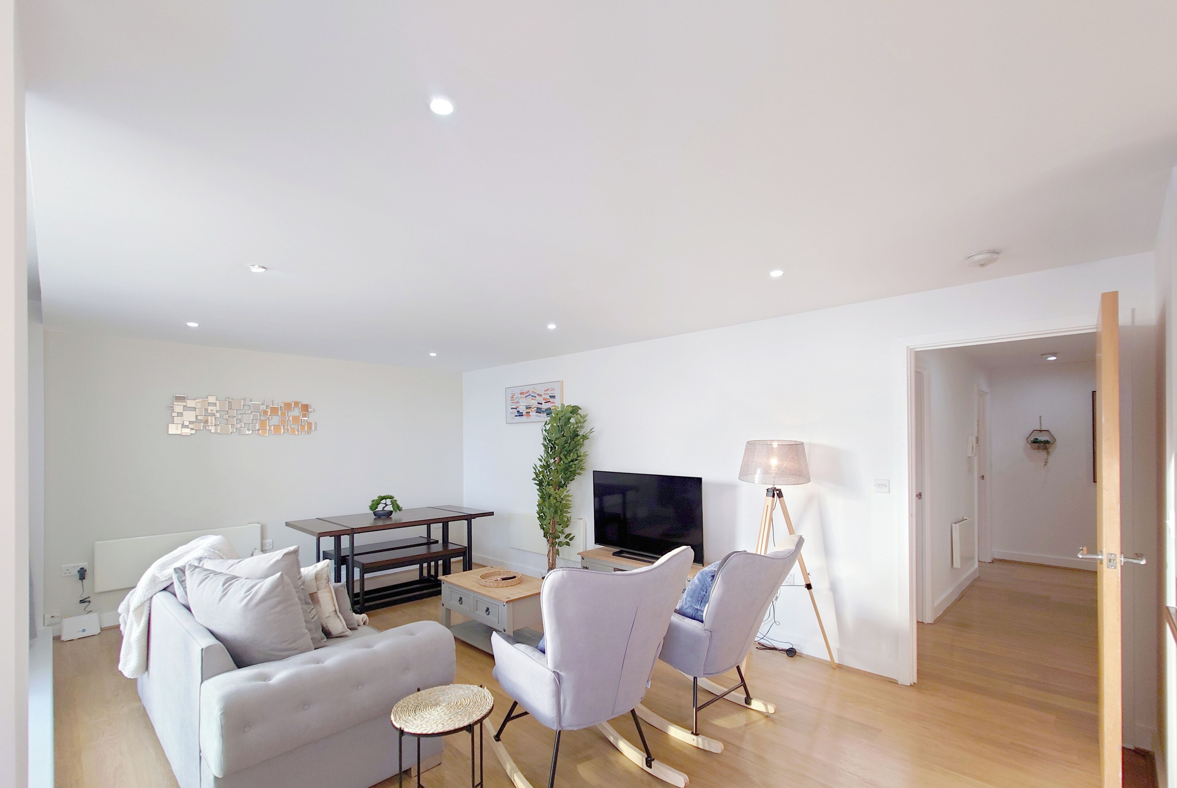 A modern living room with a sofa, chairs, a TV, and a lamp.