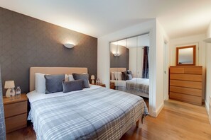 A modern hotel room with a large bed, bedside tables, a mirror, and a wardrobe. - Capital Stay Aldgate - Two Bed Apartment (London)