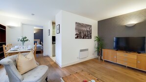 Una sala moderna con sofá, televisor y comedor.