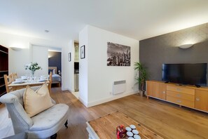 A modern living room with a sofa, TV, and dining area. - Capital Stay Aldgate - Two Bed Apartment (London)
