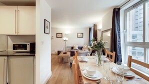 Una cocina moderna con microondas, mesa de comedor dispuesta con platos, vasos y un jarrón de flores.