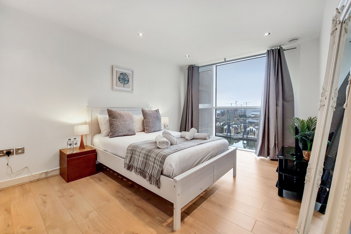 A modern bedroom with a bed, bedside table, and a large window with curtains.