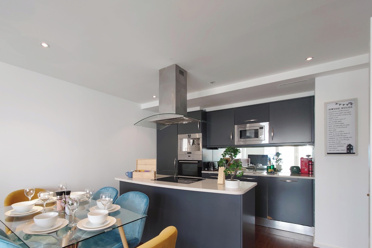 A modern kitchen with a central island, built-in appliances, and a dining area with a glass table and chairs.