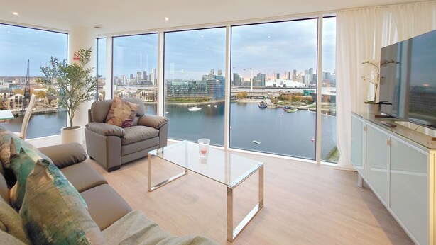 A modern living room with a sofa, a glass coffee table, and a TV on a cabinet. - Capital Stay - Two Bed Apartment In Excel (London)
