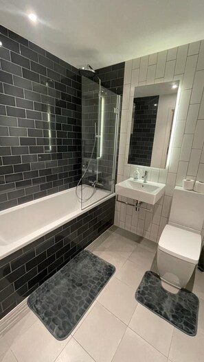 Ein modernes Badezimmer mit einer Duschkabine aus Glas, einem weißen Waschbecken und einer Toilette.