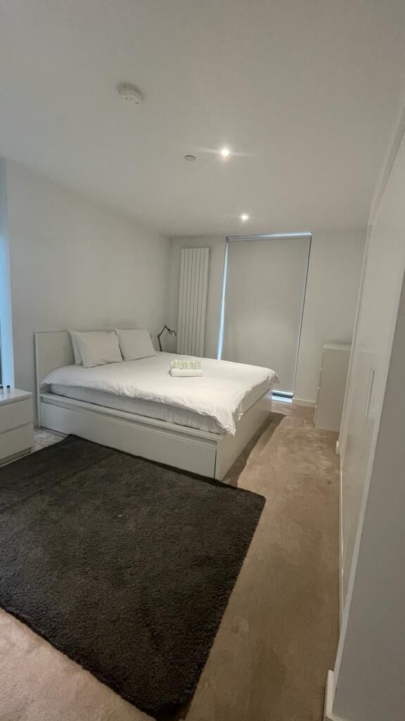 Ein Schlafzimmer mit Bett, Nachttisch und einem dunklen Teppich.